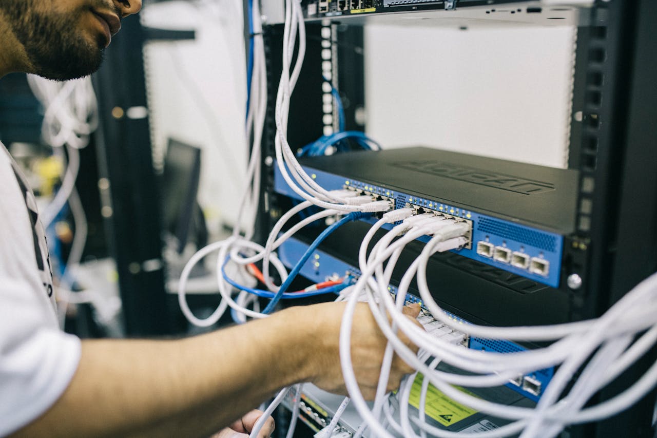 services-03 An IT professional configuring network cables in a server rack, focusing on Ethernet connections.